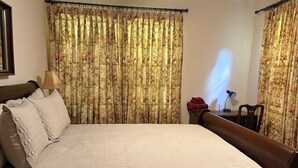 Un lit bien fait, avec une couverture matelassée, une tête de lit en bois et une table de chevet avec une lampe.