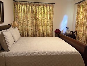 A neatly made bed with a quilted cover, a wooden headboard, and a nightstand with a lamp. - Walk to MSU, Downtown & Cotton District  Historic Home, Sleeps 6 (Starkville)