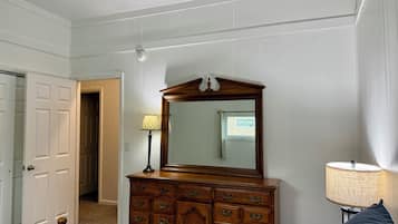 Une chambre à coucher avec une commode en bois, un miroir, une lampe et un lit.