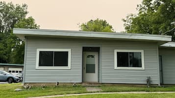 Une maison de plain-pied avec une porte d’entrée, deux fenêtres et un petit porche.