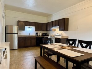 Una cocina moderna con armarios de madera oscura, electrodomésticos de acero inoxidable y una zona de comedor con mesa y sillas de madera.