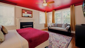 Une chambre à coucher avec un lit, un canapé, une cheminée et un ventilateur de plafond.