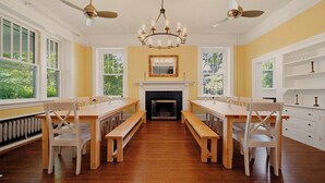 Une salle à manger avec une cheminée, des bancs en bois et un lustre.