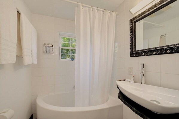 Un baño con bañera, lavamanos, espejo y cortina de ducha.
