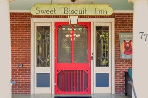 A building with a red door and a sign that reads 'Sweet Biscuit Inn.' - Sweet Biscuit Inn | 2 Homes • Sleeps 26 (Asheville)