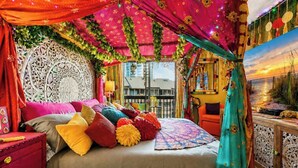 Una stanza con un letto, un comodino rosso, una tenda verde acqua e una decorazione a parete.