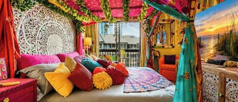 Ein Zimmer mit einem Bett, einem roten Nachttisch, einem türkisfarbenen Vorhang und einer Wandverzierung.