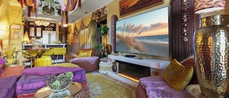 A living room with a large flat-screen TV, a sofa set, a coffee table, and a decorative cabinet.