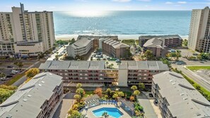 Un hotel con piscina, varias construcciones y vista al mar.