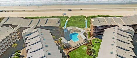 Ein Resort mit mehreren Gebäuden, einem zentralen Pool und Blick auf den Strand.