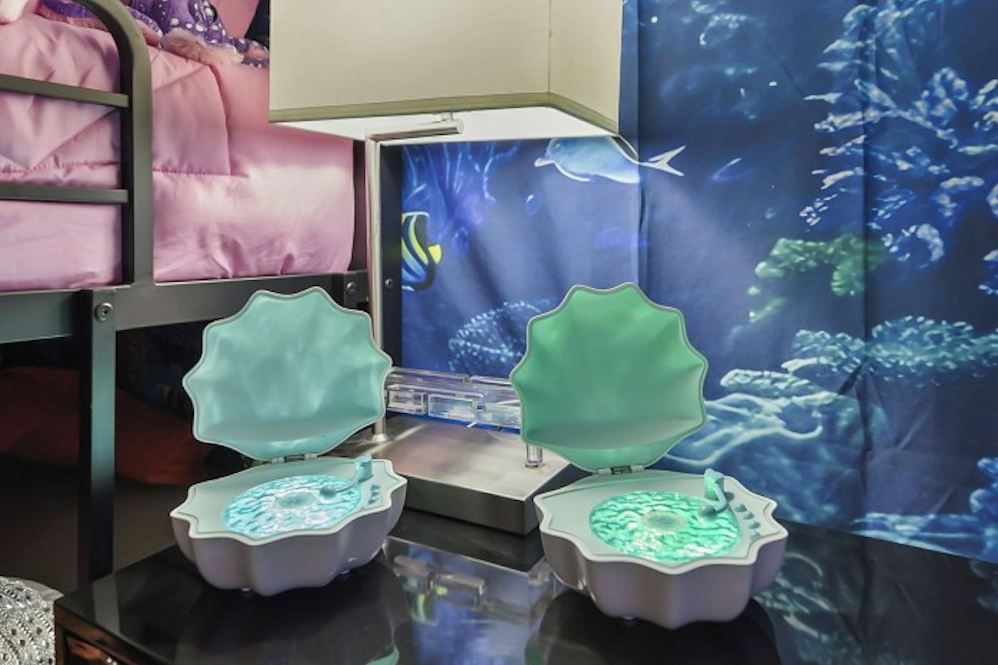 Una habitación con literas, una pantalla de acuario digital y una mesa con objetos iluminados.