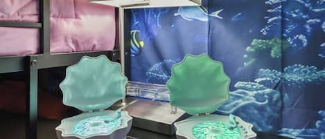 A room with bunk beds, a digital aquarium display, and a table with illuminated objects.