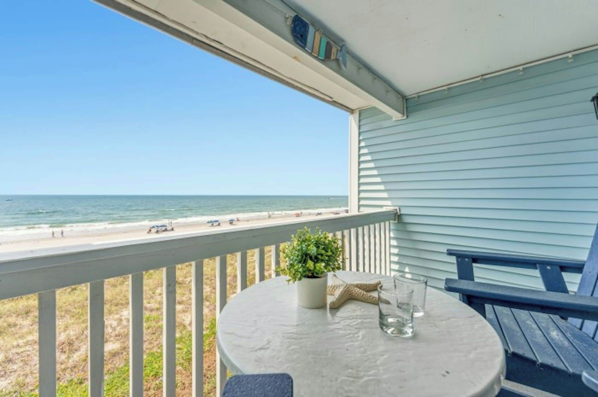A balcony with a view of the beach and ocean.