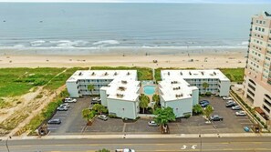 Ein Hotel direkt am Strand mit Swimmingpool, mehreren Parkplätzen und Blick auf den Ozean.