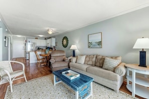 A living room with a sofa, coffee table, and a dining area with chairs and a table. - Ocean Garden Villas B3- Oceanfront 2 Bedroom (North Myrtle Beach)