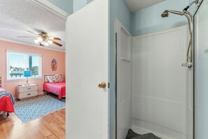A bedroom with a bed, a nightstand, a ceiling fan, and a window with blinds. - Ocean Garden Villas B3- Oceanfront 2 Bedroom (North Myrtle Beach)