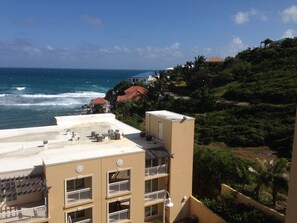 A coastal building with multiple balconies, a view of the ocean, and surrounding greenery. - 3-bedroom Ocean Front Villa, Dawn Beach Club at JW Marriott. Fixed 6403 (oyster pond)