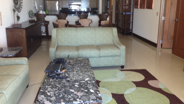 Sala de estar com sofá, mesa de centro e cozinha ao fundo.