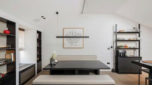 Une cuisine moderne avec un mur en briques blanches, des meubles de rangement noirs et un coin repas avec un banc.
