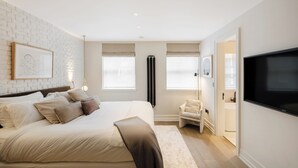 Une chambre dotée d’un grand lit, d’un téléviseur à écran plat, d’une fenêtre offrant une vue agréable et d’une porte donnant accès à une salle de bain.