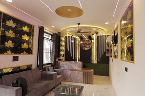A hotel lobby with a reception desk, seating area, and a large mirror with leaf patterns. - Hotel The Grand Bareilly (Bareilly)