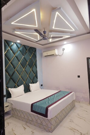 A bedroom with a bed, a ceiling fan, and an air conditioning unit. - Hotel The Grand Bareilly (Bareilly)