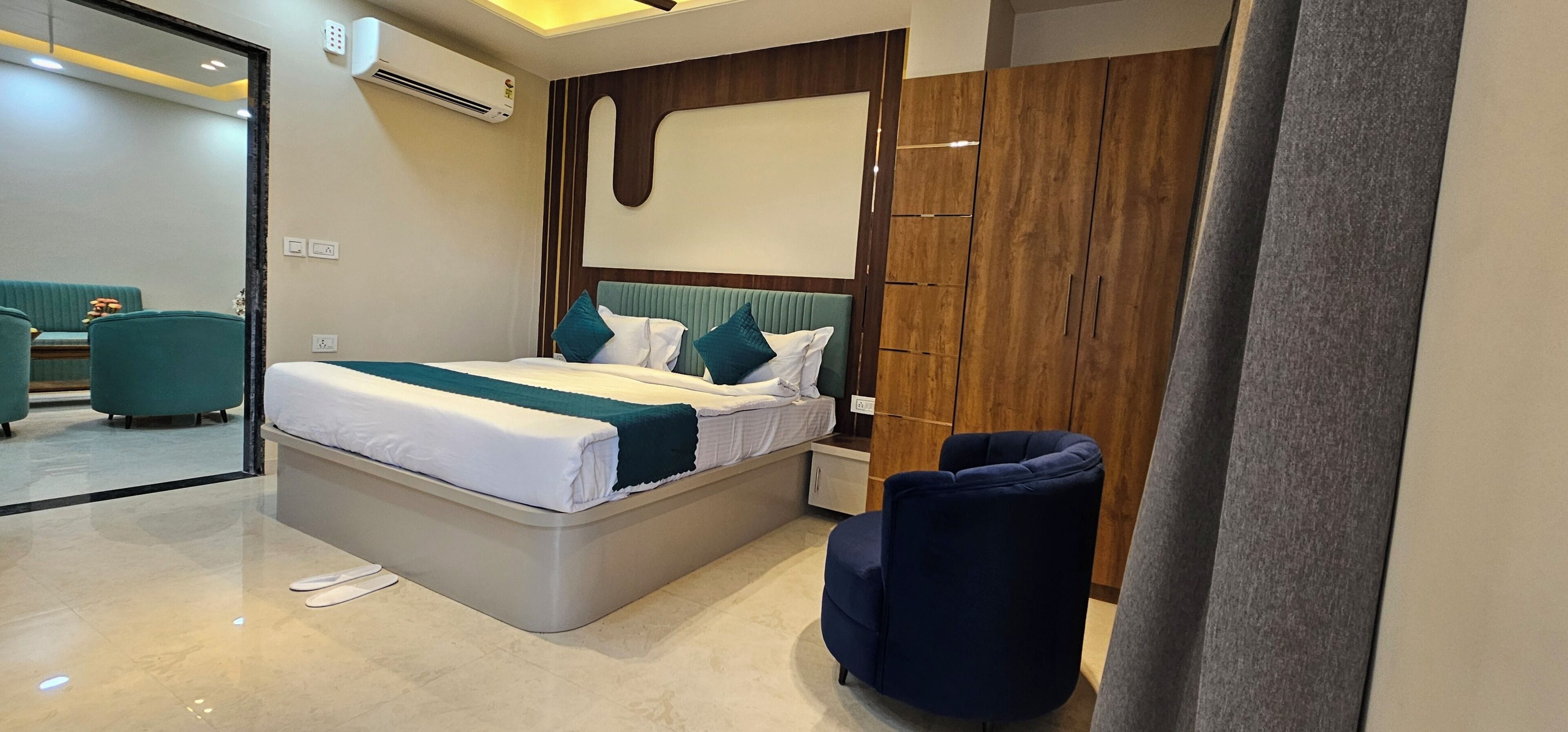 Un dormitorio moderno con cama, mesitas de noche, armario y una zona de estar con una silla.