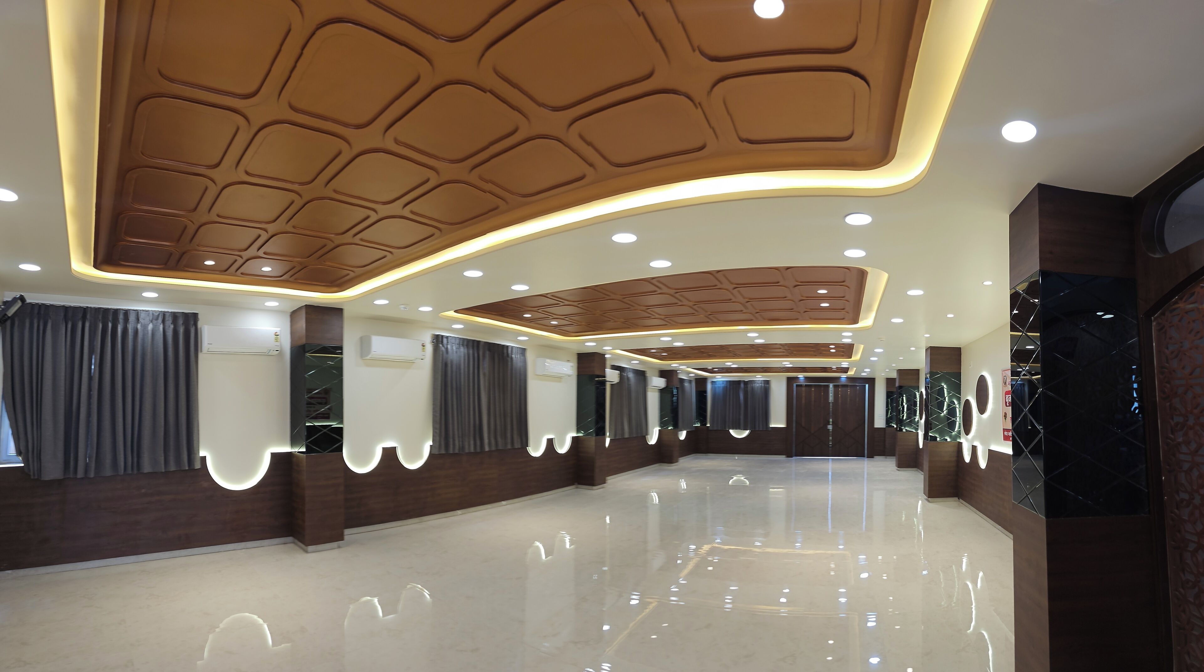 Um hall de hotel com piso lustroso, iluminação embutida e teto padronizado.