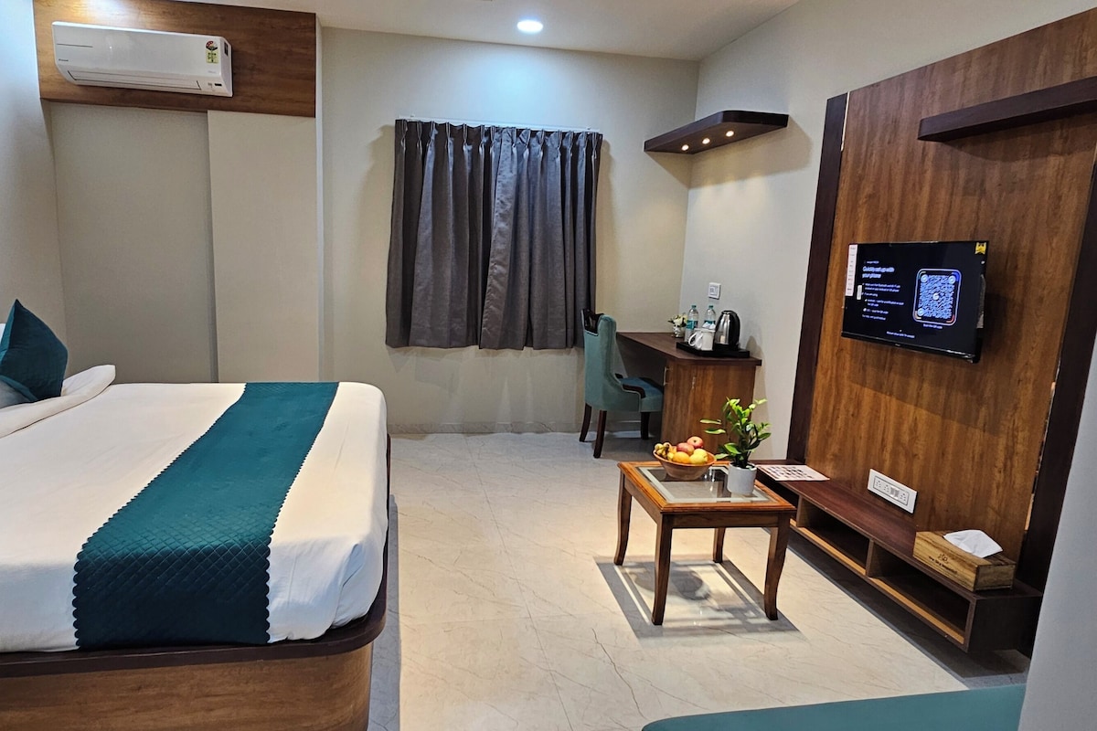 A hotel room with a bed, a desk, a chair, a television, and a window with curtains.