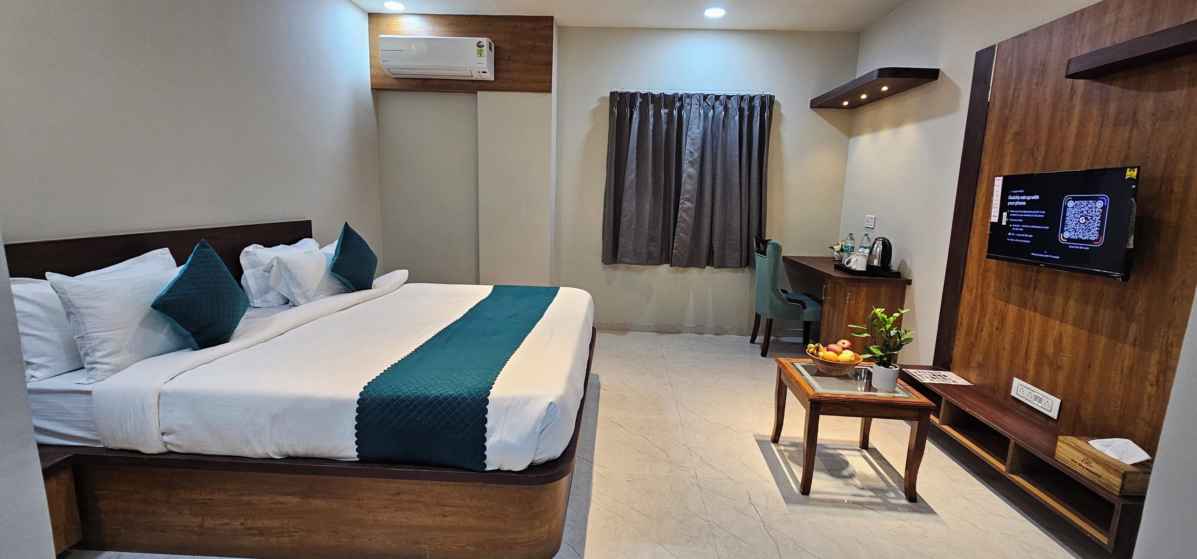 Habitación de hotel con cama, escritorio, silla, televisor y aire acondicionado instalado en la pared.