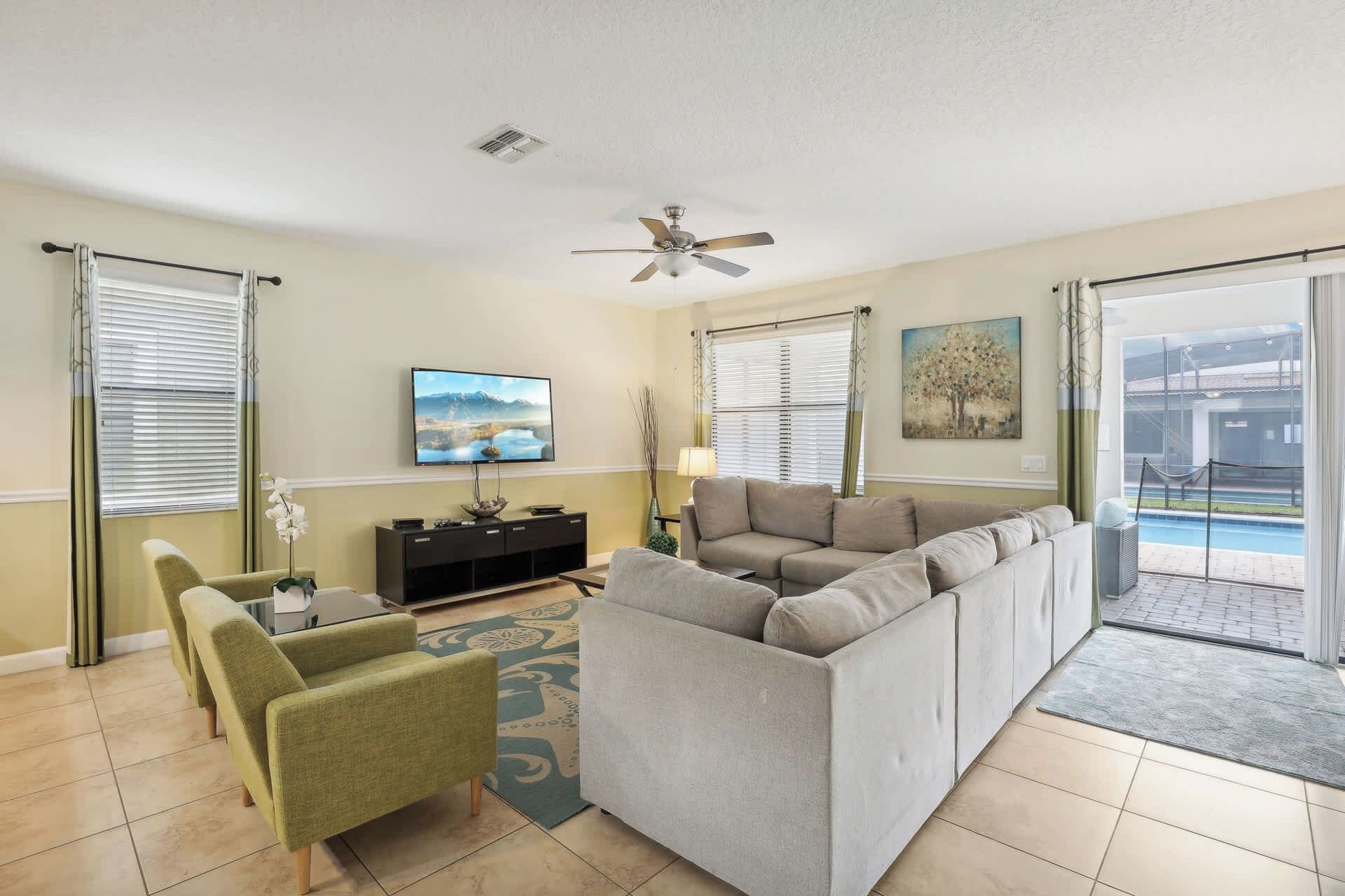 A living room with a gray sectional sofa, a green armchair, a TV, and a painting on the wall.
