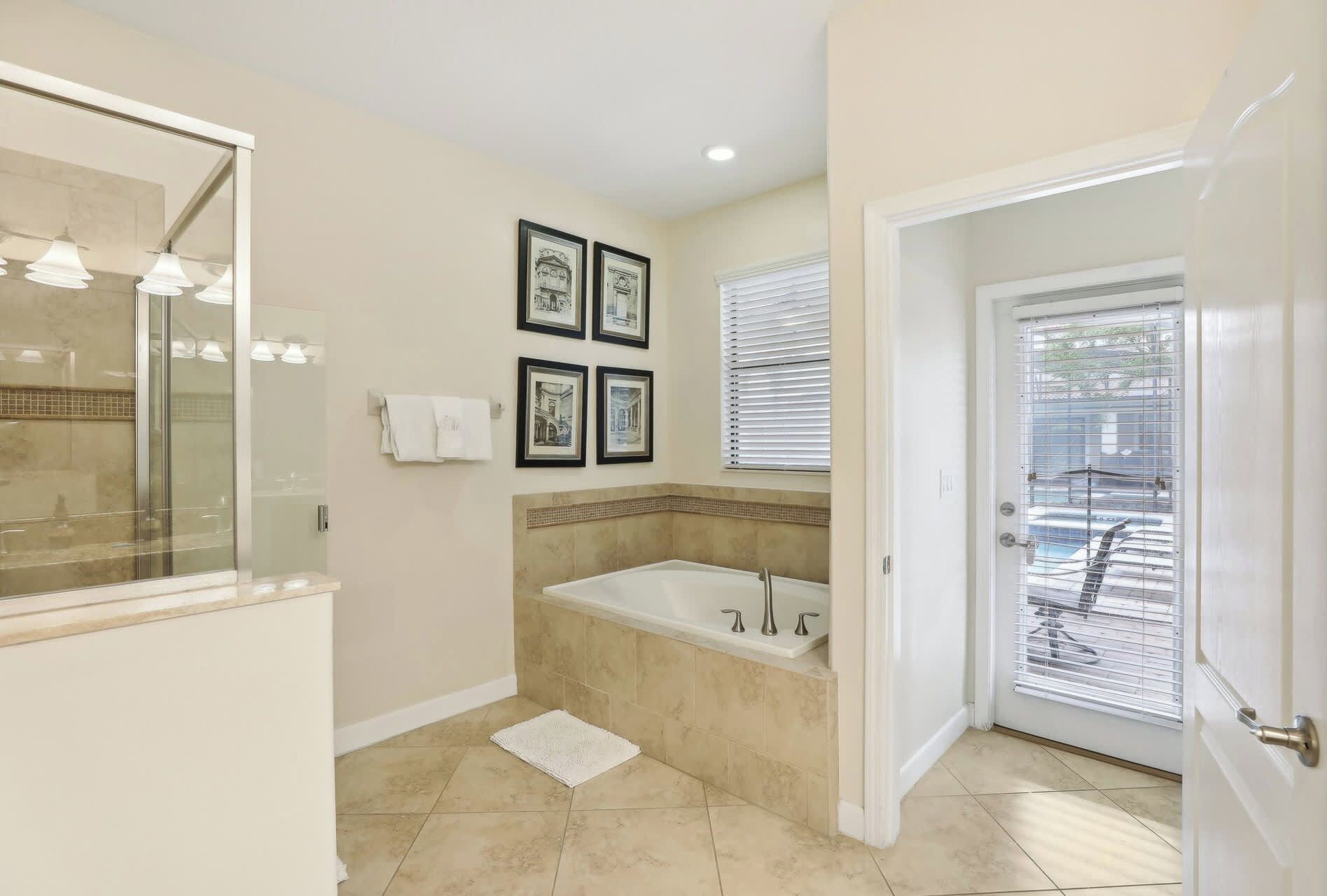 A bathroom with a bathtub, a large mirror, and framed pictures on the wall.