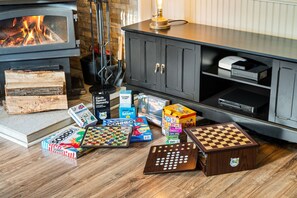 A cozy living room with a fireplace, a cabinet with electronic devices, and various board games on the floor. - Camelback Home, Family Friendly, Waterpark, Arcade (Tannersville)