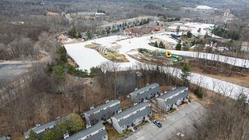 An aerial view of a residential area with multiple buildings, a parking lot, and a playground.
