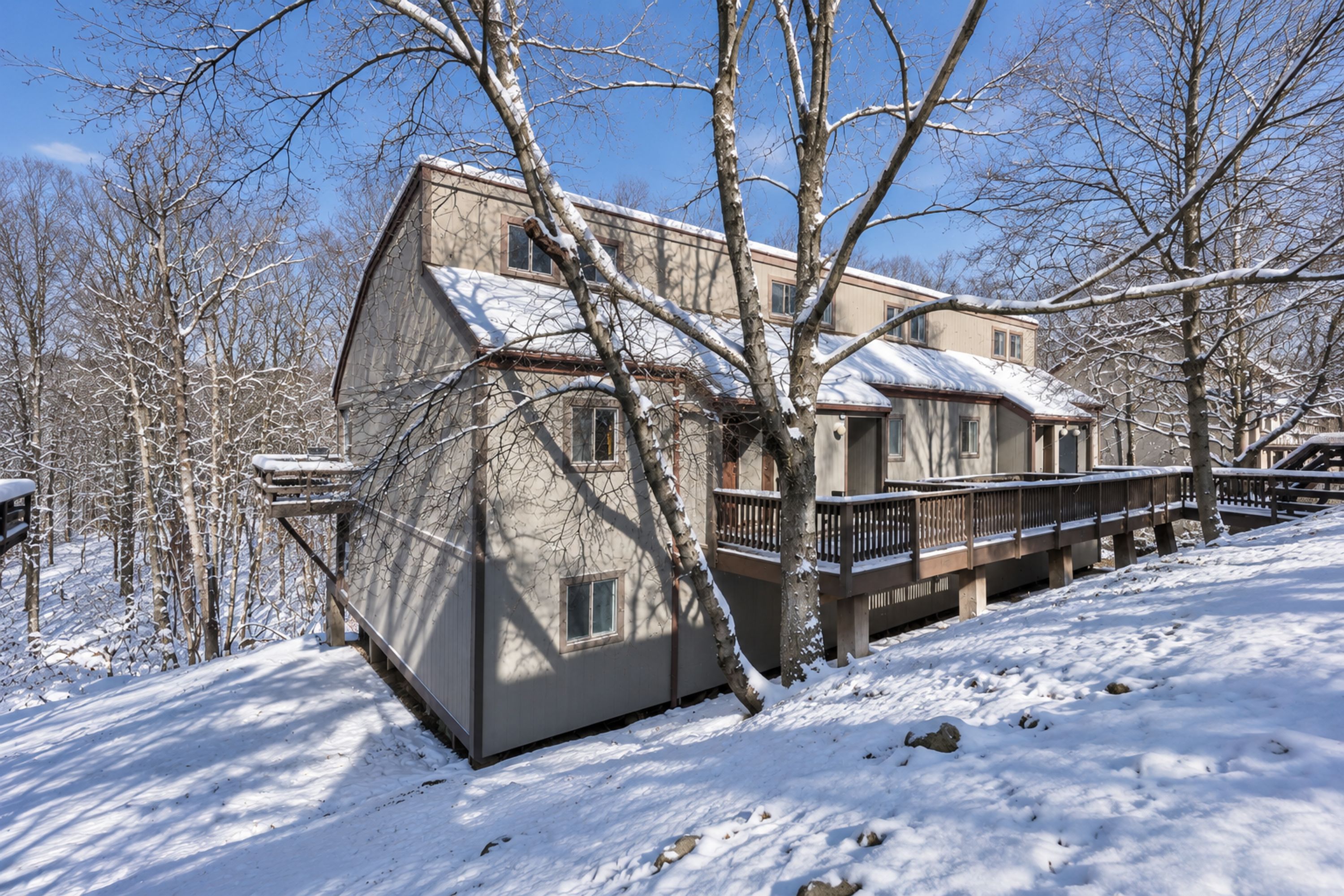 A two-story house with a snow-covered roof and a deck.