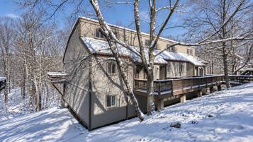 A two-story house with a snow-covered roof and a deck.
