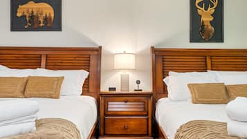 A hotel room with two wooden beds, a nightstand with a lamp, and two wall-mounted animal-themed decorations.
