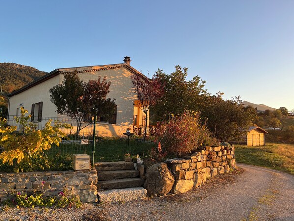 Une maison en pierre avec une allée pavée et un mur en pierre.
