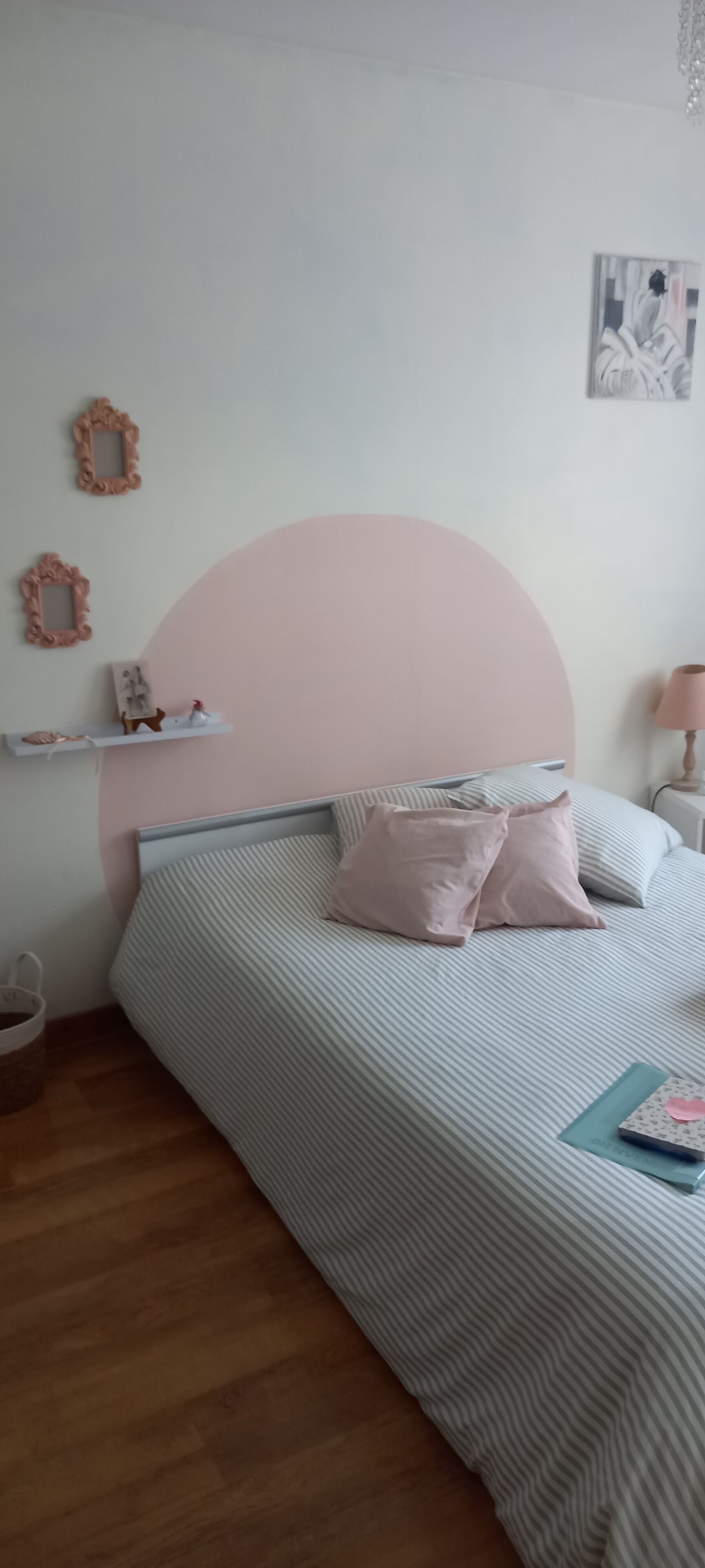 A bedroom with a bed, a bedside table, a lamp, and wall decorations.