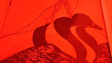 Une œuvre d’art encadrée, représentant des figures abstraites et des chaînes.