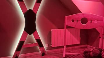 Een kamer met een stapelbed, een schuine plafond en een radiator.