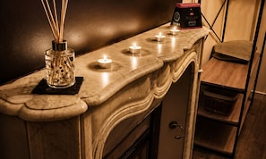 A marble counter with candles, a diffuser, and a small box, likely a minibar.