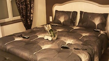 Een slaapkamer met een bed, een bankje en een raam met gordijnen.