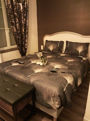 A bedroom with a bed, a bench, and a window with curtains.