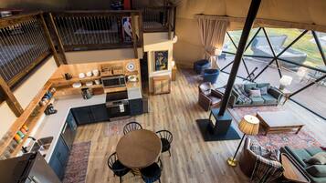 Un hébergement spacieux sous tente, comprenant une cuisine, un coin repas et un espace salon.