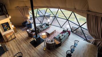 A spacious interior with a wooden floor, a sofa set, a dining table, and a fireplace.