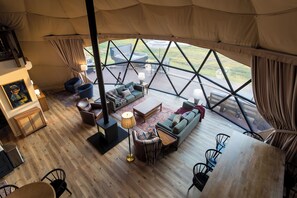 A spacious interior with a wooden floor, a sofa set, a dining table, and a fireplace.