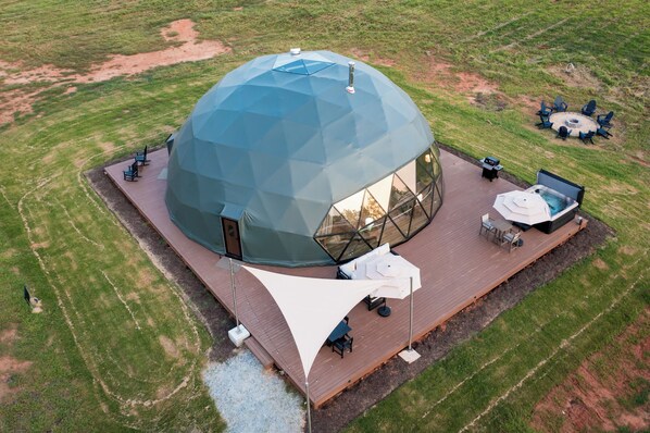 A geodesic dome structure with a deck and outdoor seating area.