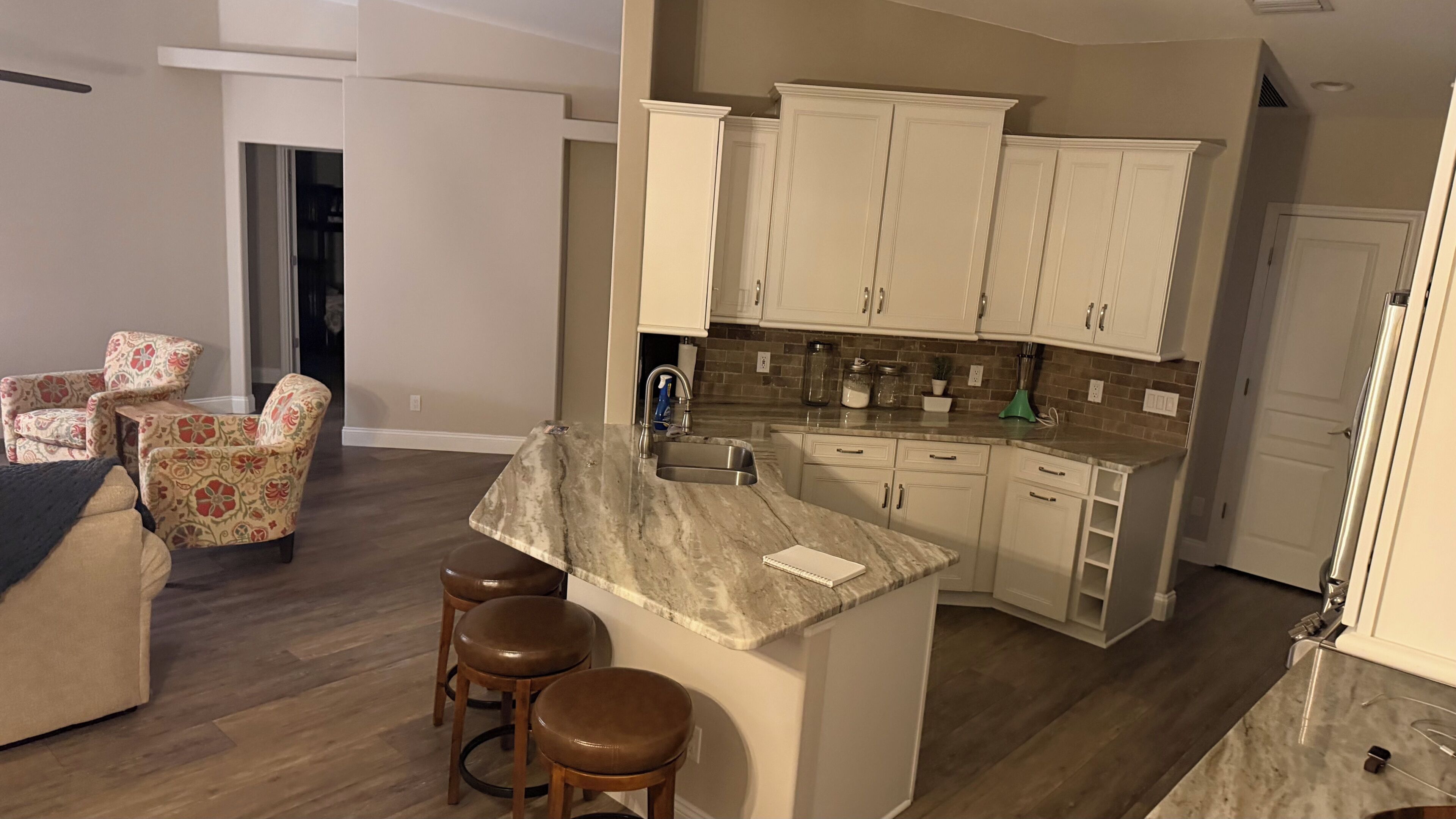 A modern kitchen with white cabinets, a marble countertop, and a built-in sink.