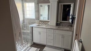 Un baño con ducha, lavabo y espejo.